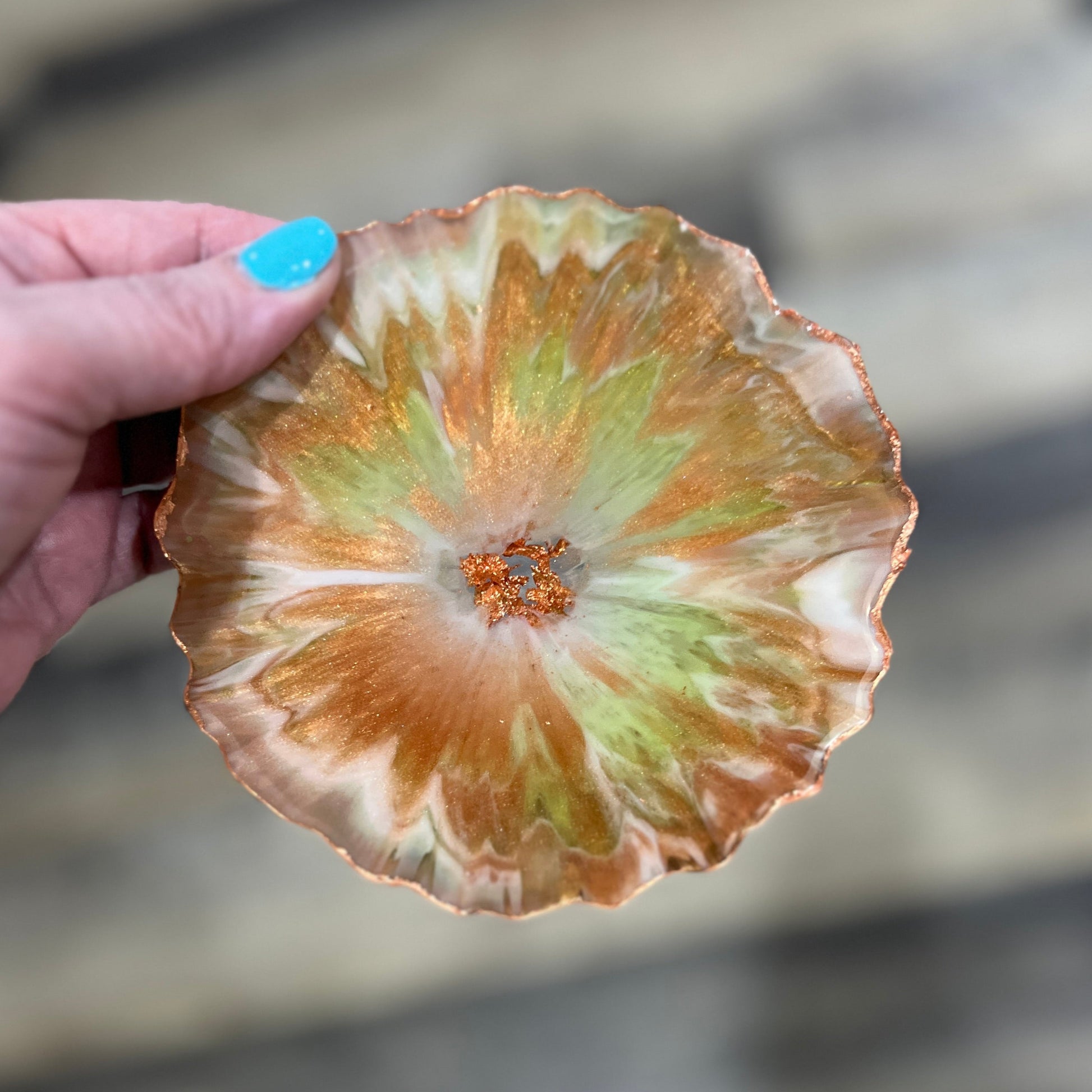Close-up of a green and copper coaster showing layered resin details and copper edging