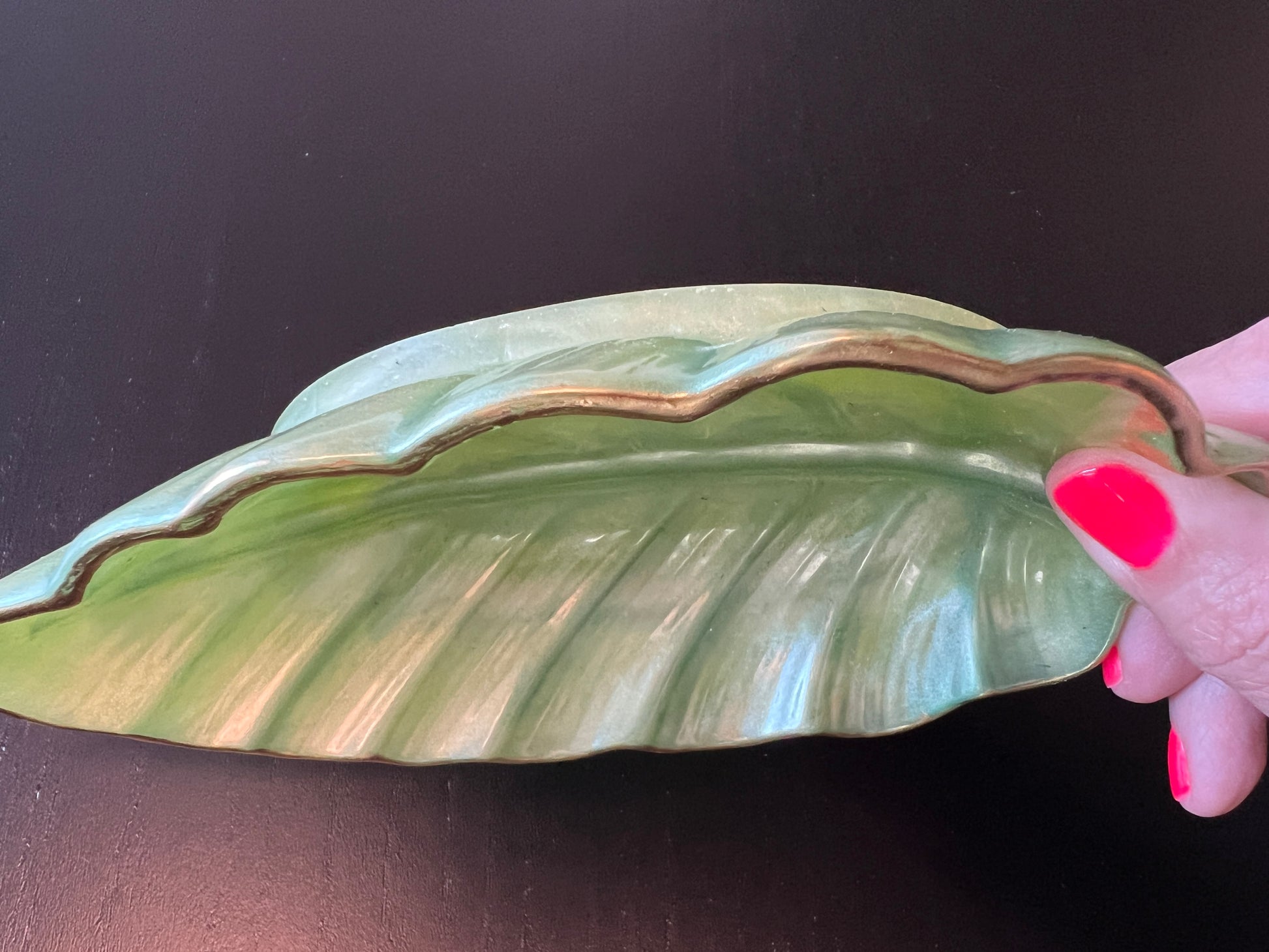 Close-up detail of gold-painted trim on light green resin leaf tray