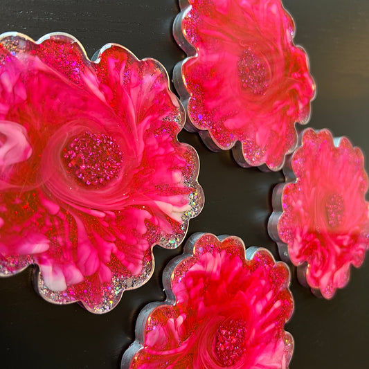 Four pink flower-shaped coasters on a dark surface