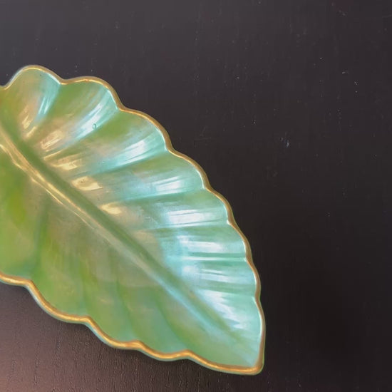 Video of small light green resin leaf tray with gold trim placing items to show size